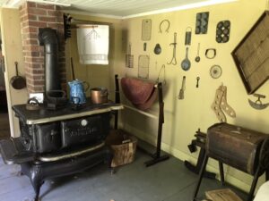 Victorian kitchen with stove and kitchen implements hanging on the wall